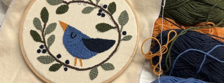 tuftattu lintuaiheinen taulu kirjontakehyksessä